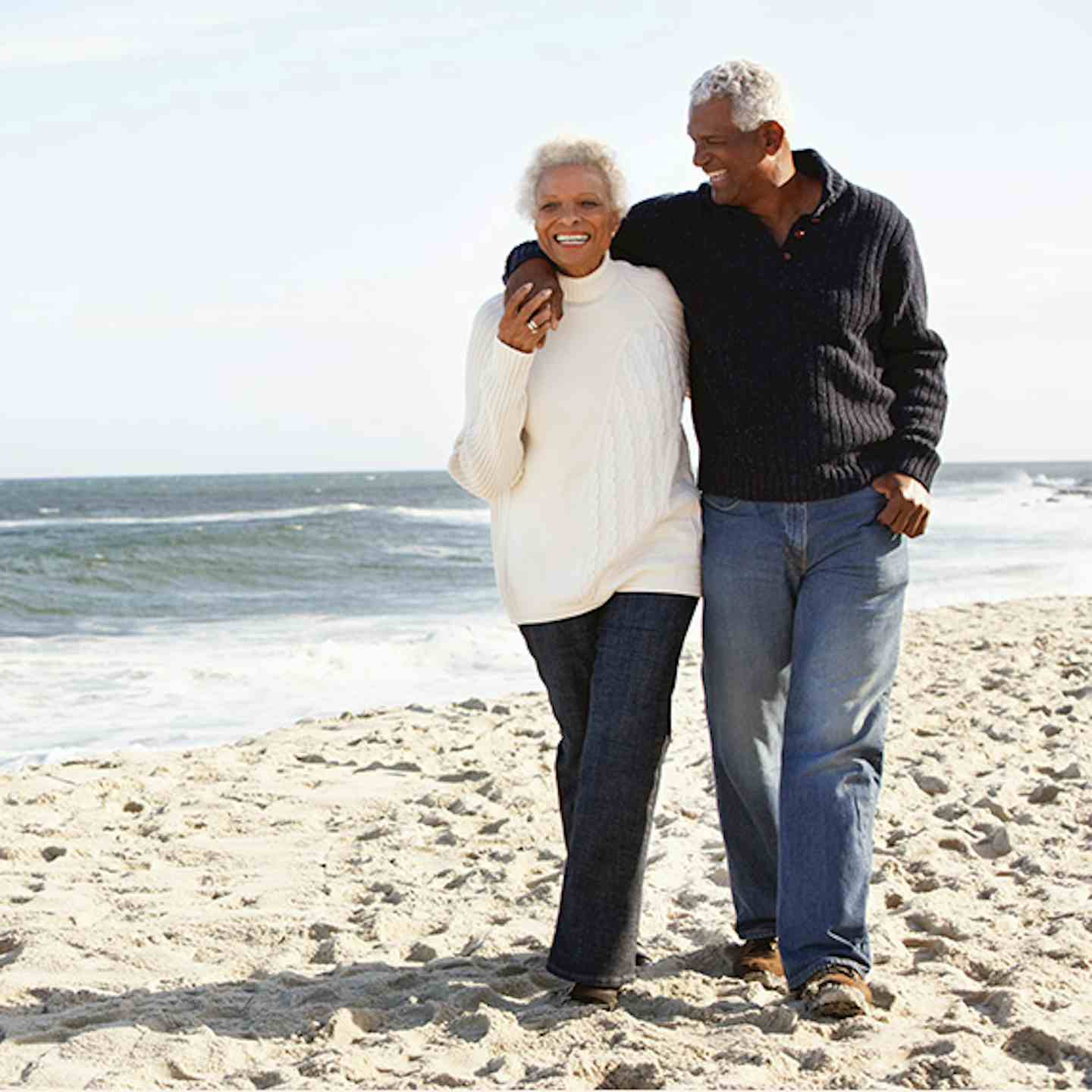 Mature couple walking on the beach discusing cancer prevention